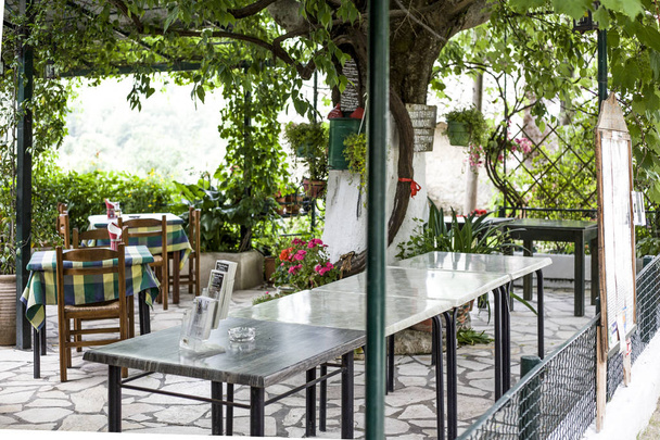 パレオカストリッツア、Cofru、ギリシャ-2018 年 5 月 10 日中のタベルナ テーブルを持つギリシャ料理のレストランと庭が付いている椅子の一見。小さなグループの人々 のためのレストランを設定します。 - 写真・画像