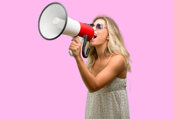 Молода жінка в сонцезахисних окулярах з формою серця спілкується з криком вголос тримаючи мегафон, висловлюючи успіх і позитивну концепцію, ідею для маркетингу або продажів
 - Фото, зображення
