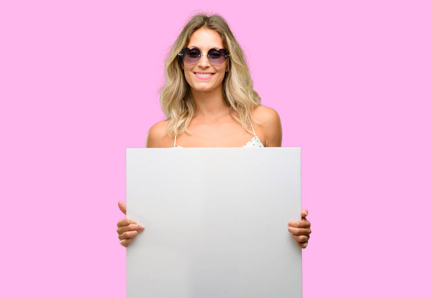 junge Frau mit Sonnenbrille in Herzform mit leerem Werbebanner, gutes Plakat für Werbung, Angebot oder Ankündigung, große Papierwerbetafel - Foto, Bild