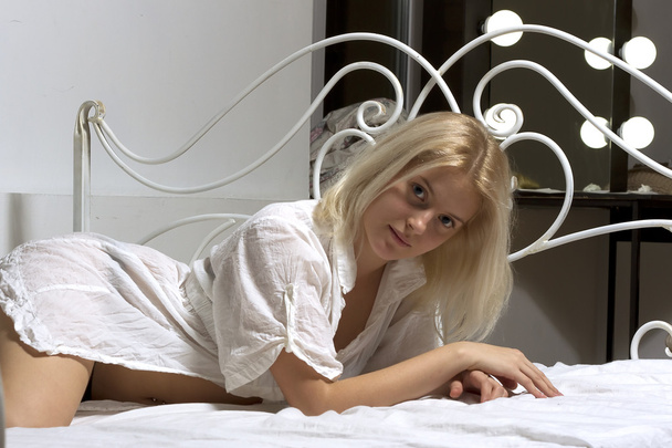 Blonde girl in the bed next to wrought headrest - Foto, immagini