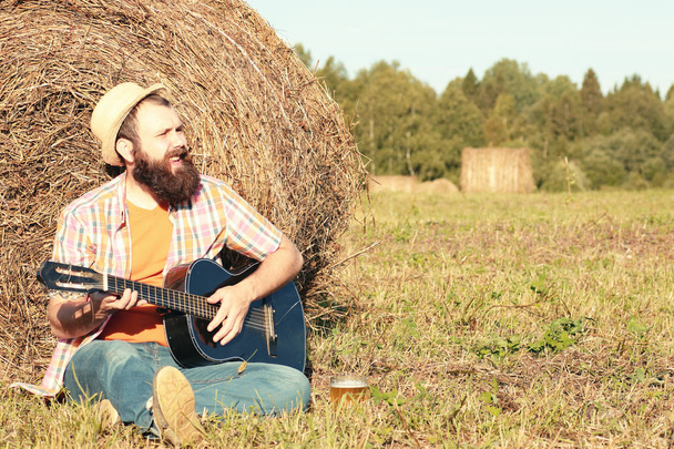 uomo con chitarra e birra sulla natura
 - Foto, immagini