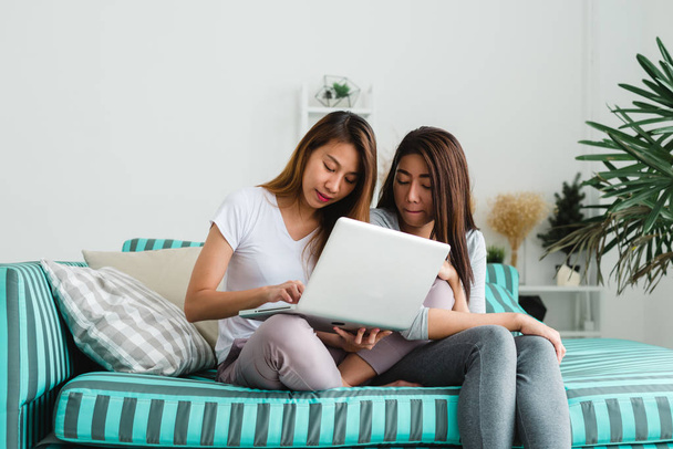 Krásné mladé asijské ženy Lgbt lesbické šťastný pár sedí na pohovce nákup online pomocí přenosného počítače a kreditní karty v obývacím pokoji doma. LGBT lesbické pár dohromady uvnitř koncepce. - Fotografie, Obrázek