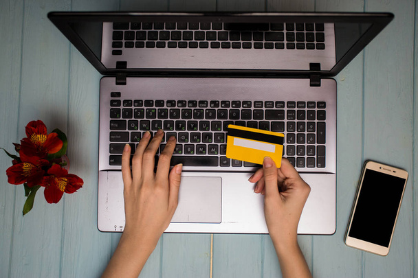 Рука женщины держит кредитную карту над столом, онлайн покупки подарков по телефону во время кофе-брейка. Концепция новых технологий. Плоский лежал
 - Фото, изображение