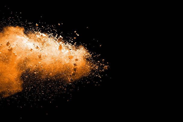 Explosion of orange and brown dust on black background. - Photo, Image