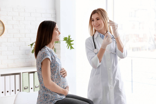Doctor vaccinating pregnant woman in clinic - Fotó, kép