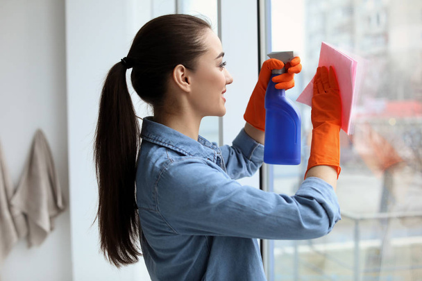 Mujer joven limpiando vidrio de ventana en casa
 - Foto, imagen