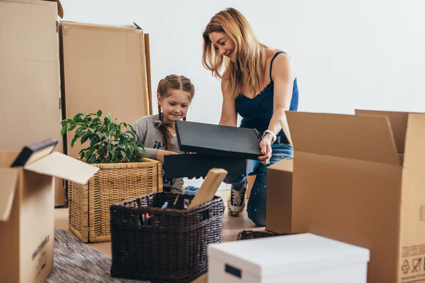 Family unpacking cardboard boxes at new home - Photo, Image