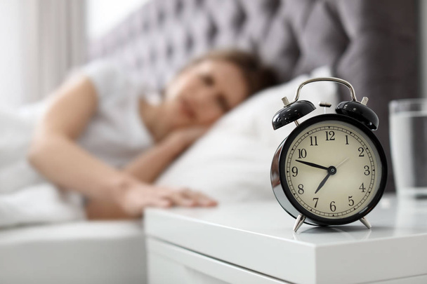 Alarm clock on nightstand of young woman suffering from headache - Foto, Bild