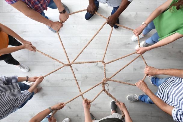 People holding rope together indoors, top view. Unity concept - Foto, Imagen