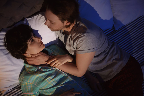 Jovem casal apaixonado na cama à noite
 - Foto, Imagem