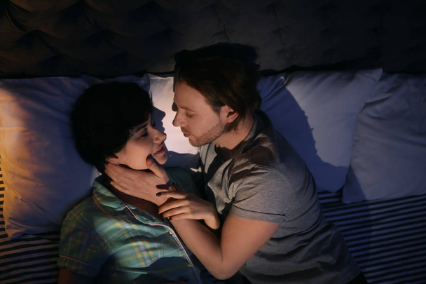 Young couple in love on bed at night time - Fotoğraf, Görsel