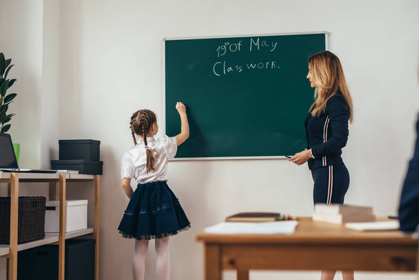 Iskolai lecke tanár és a tanuló írni a táblára - Fotó, kép