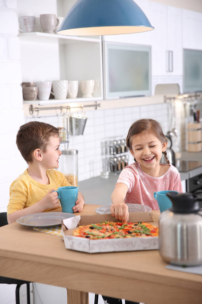 Cute little kids eating tasty pizza at home - Foto, imagen
