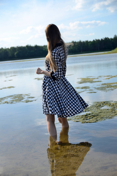 weibliches Modell steht im Wasser. Frau trägt Kleid mit schwarz-weißem Muster. - Foto, Bild