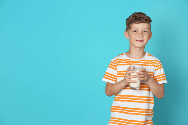 Adorable little boy with glass of milk on color background - Fotó, kép
