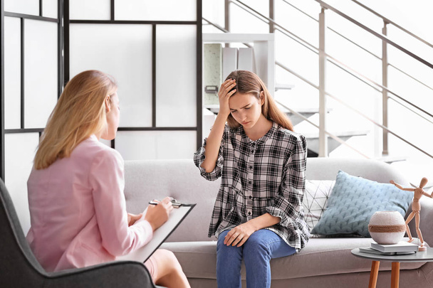 Child psychologist working with teenage girl in office - Foto, afbeelding