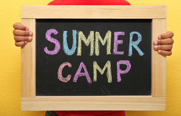 Çocuk holding blackboard kelimelerle yaz kampı farklı renklerde, closeup chalked. - Fotoğraf, Görsel