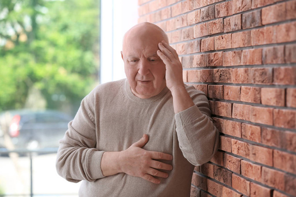 Старший чоловік у стані депресії біля цегляної стіни
 - Фото, зображення
