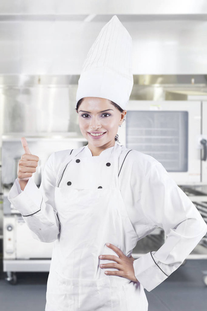 Image de femme chef montre pouce levé tout en se tenant dans la cuisine
 - Photo, image