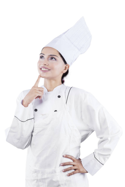 Portrait of female chef thinking something while standing in the studio, isolated on white background - 写真・画像