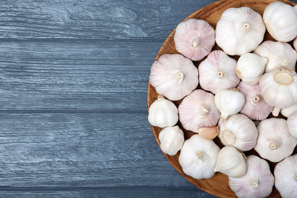 Plate with fresh garlic bulbs on wooden background, top view - Fotografie, Obrázek