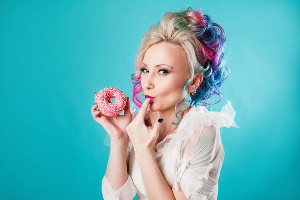 Cool young woman with colored hair, taste sweet donut, funny - Фото, изображение