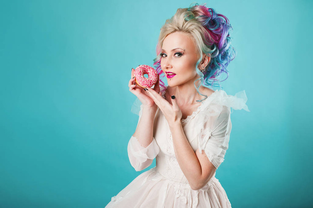 Cool young woman with colored hair. Holds sweet donut, funny - Photo, Image