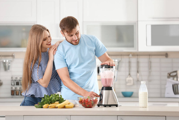 Young couple preparing delicious milk shake in kitchen - Zdjęcie, obraz