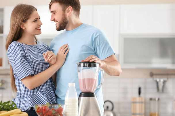 若いカップルの台所で準備おいしい牛乳を振る - 写真・画像