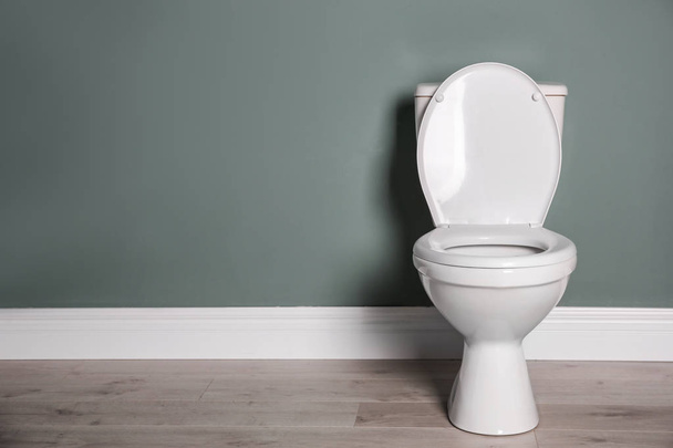 New ceramic toilet bowl near grey wall - Фото, изображение