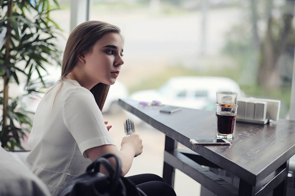 Молодая девушка в кафе. Девушка сидит на диване и разговаривает по телефону
. - Фото, изображение