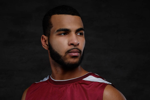 Close-up portrait of an Afro-American basketball player. Isolated over dark background. - Zdjęcie, obraz