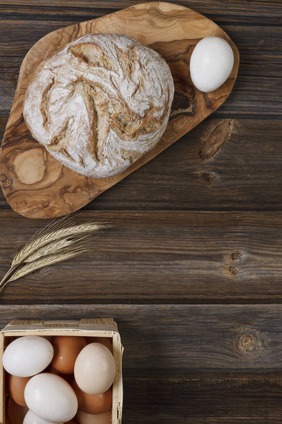 close-up photo of fresh homemade bread with eggs on wooden table background - Fotó, kép