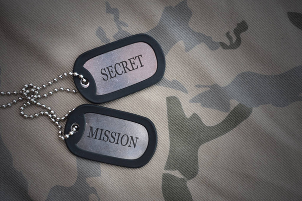 Armee leer, Hundeanhänger mit Text in geheimer Mission auf dem khakifarbenen Hintergrund. Militärisches Konzept - Foto, Bild