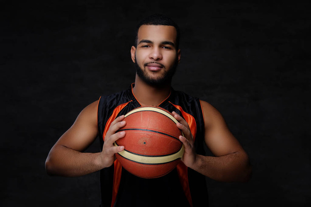 アフリカ系アメリカ人のスポーツマンの肖像画。暗い背景にボールとスポーツのバスケット ボール選手. - 写真・画像