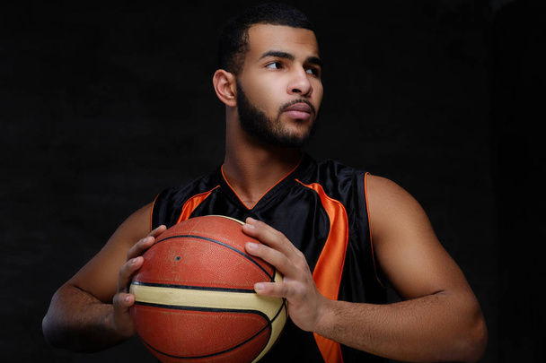 暗い背景上分離したスポーツウェアの若いアフリカ系アメリカ人のバスケット ボール選手の肖像画.  - 写真・画像