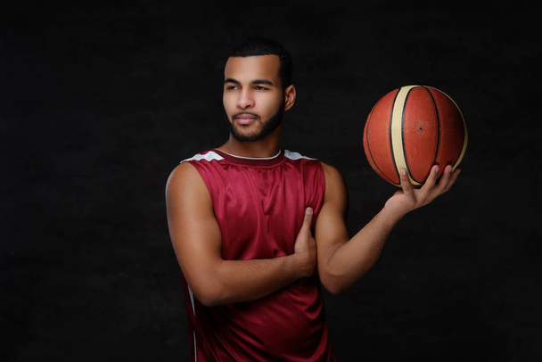 暗い背景上分離したスポーツウェアの若いアフリカ系アメリカ人のバスケット ボール選手の肖像画.  - 写真・画像