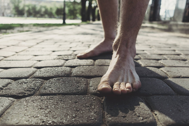 Man bare feet stepping on pavement - Foto, afbeelding