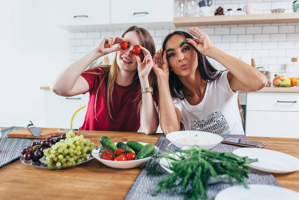 Chicas tonteando en la cocina jugando con verduras
. - Foto, imagen
