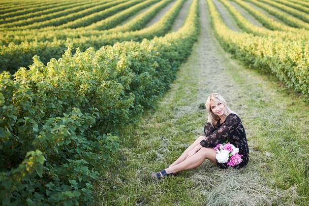 Carino ragazza bionda trascorre del tempo in un pittoresco campo con un mucchio di pioni nelle sue mani
 - Foto, immagini