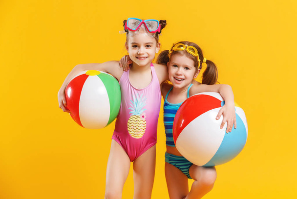 lustig lustige fröhliche Kinder in Badeanzügen und Schwimmbrillen springen auf farbigem Hintergrund - Foto, Bild