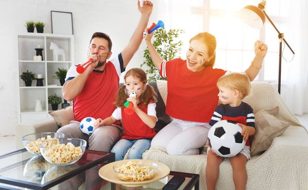 A family of fans watching a football match on TV at hom - 写真・画像