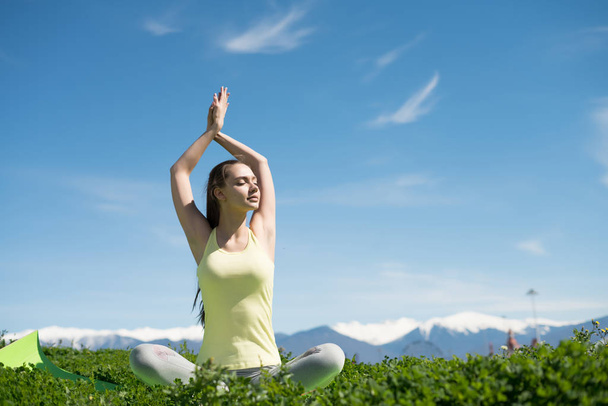 slender young girl meditates and relaxes in the park in the sun, does yoga - Photo, image