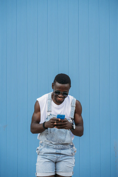 Портрет красивого афро чоловіка, який використовує свій мобільний
. - Фото, зображення