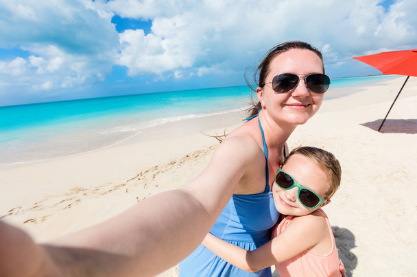 Feliz familia madre y su adorable hijita en la playa tomando selfie
 - Foto, Imagen