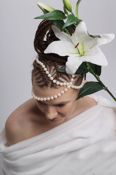 meisje met exotische kapsel op witte achtergrond, bloemen lily, witte jurk, Griekse stijl, Afrikaanse kapsel, meisje met vaas, meisje met kruik - Foto, afbeelding