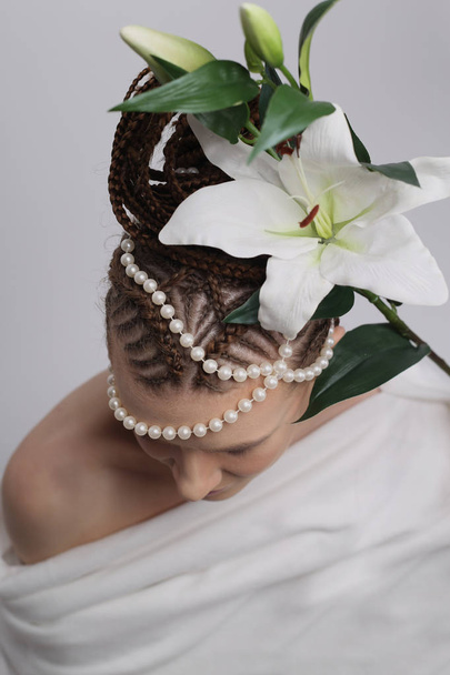 kız beyaz arka planda, egzotik saç modeli ile çiçekler lily, beyaz elbise, Yunan Biberi, Afrika saç modeli, kızla vazo, sürahi ile kız - Fotoğraf, Görsel