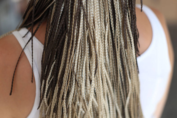 het patroon van haar pigtails, krullen. kapsel, het resultaat van het werk van een kapper, close-up van een textuur, op een witte achtergrond - Foto, afbeelding