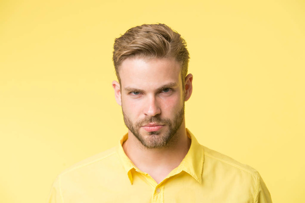 Masculinity concept. Man with beard or unshaven guy looks handsome and well groomed. Guy bearded and attractive cares about his appearance. Man with bristle on confident face, yellow background - Fotoğraf, Görsel