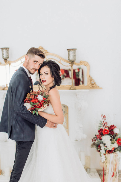 Beautiful and young bride and groom posing at room - Фото, изображение